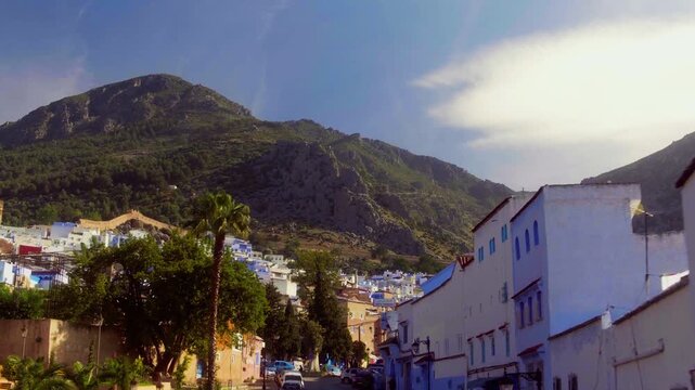 Blue medina of Chefchaouen with Rif mountain, camera tracking back along street