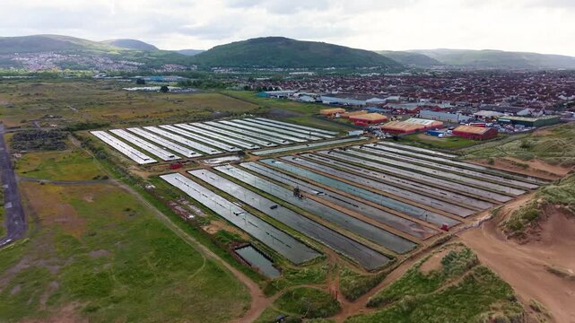Drone View of Commercial Ragworm Farm and Marine Bait Production. Sediment beds and water filtration systems used to cultivate ragworms for the global fishing bait market. United Kingdom. 4K.