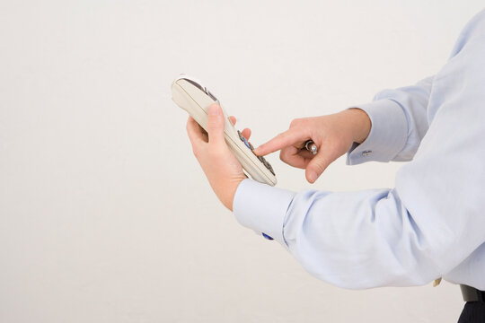 Mid section view of a businessman operating an adding machine tape