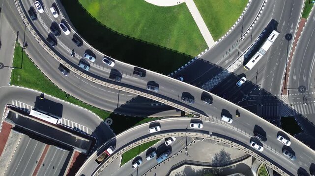 Raw unedited 4K drone footage of a smooth vertical descent in bird's eye view, approaching busy highway lanes and a major road interchange in central Tbilisi, Georgia. Heavy traffic moves through the 
