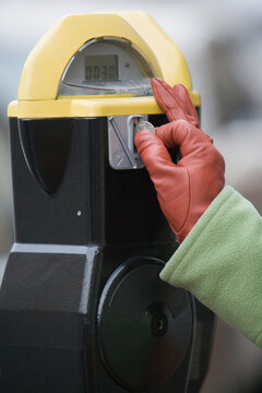Close-up of a person's hand inserting a coin into a parking meter