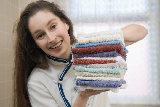Portrait of a mid adult woman holding a stack of washcloths and smiling