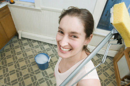 Portrait of a mid adult woman holding a mop and smiling