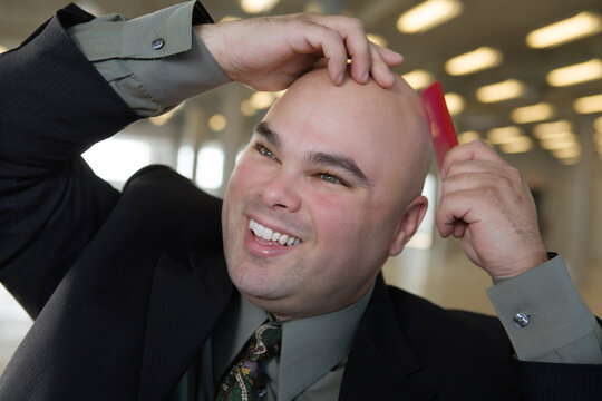 View of a businessman combing baldhead