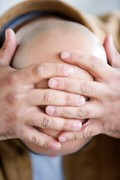 Bald headed man with hands on head