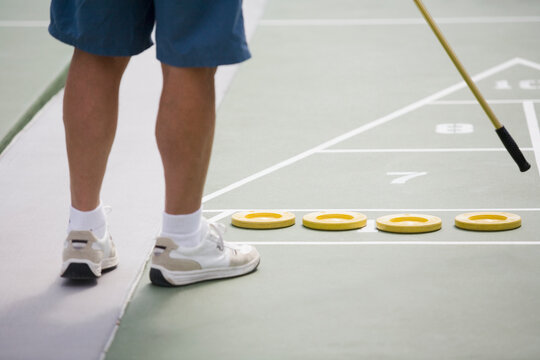 Low section view of a senior man playing shuffleboard