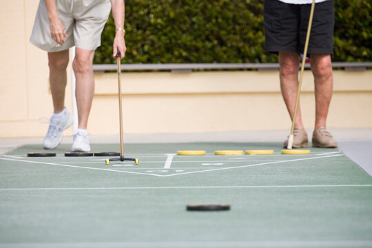 Low section view of a two senior men playing shuffleboard