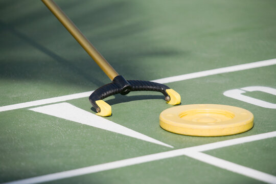Close-up of a shuffleboard disc and shuffleboard cue