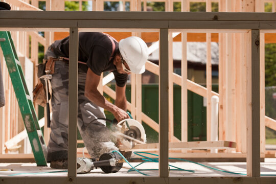 Carpenter sawing a plank at a construction site