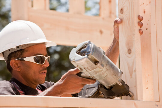 Carpenter using a nail gun at a construction site