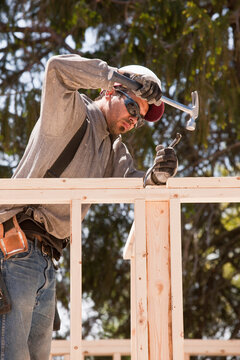 Carpenter hammering a pry bar to adjust studs