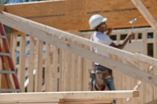 Carpenter hammering beam on house framing