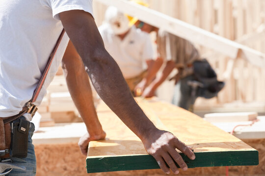 Carpenters holding a plank at a construction site