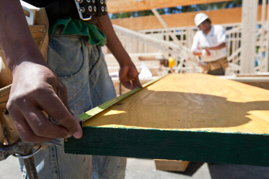 Carpenter measuring a laminated beam at a construction site