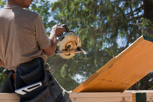 Carpenter sawing a beam at a construction site