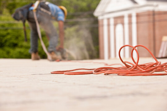 Power cord with a carpenter sawing a board in the background