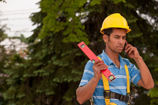 Carpenter holding a level and talking on a mobile phone