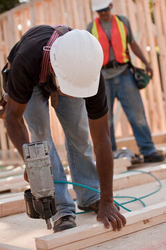 Carpenter nailing two studs together with a nail gun