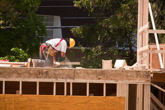 Carpenter Sawing with circular saw on second floor