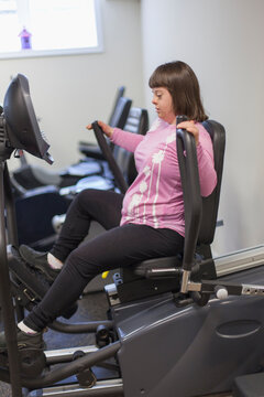 Girl with Down Syndrome working out on an exercise machine