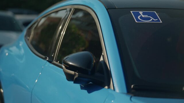 Handicap parking permit displayed on a blue parked car windshield in city street