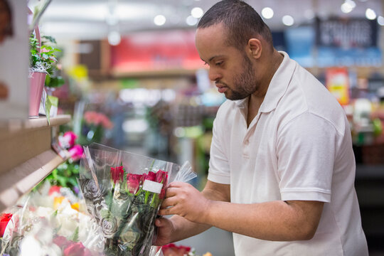 Man with Down Syndrome picking out flowers in a store