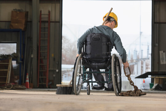 Maintenance supervisor with spinal cord injury moving tow chain in utility truck garage