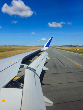 Airplane wing with flaps extended on the runway under a clear blue sky, preparing for departure and journey. Take off landing travel