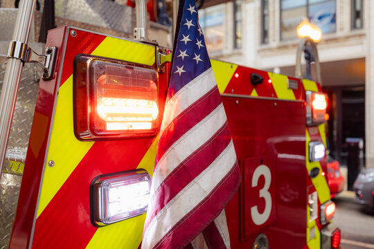 Close-up of United States of America flag on flashing fire truck on city street. Emergency services, patriotism, first responders and public safety concept.