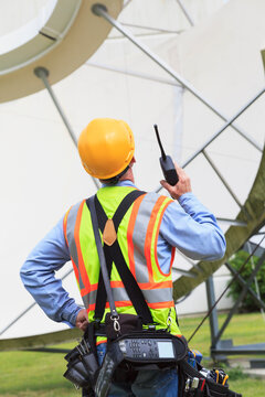Communications engineer using walkie-talkie at satellite antenna facility