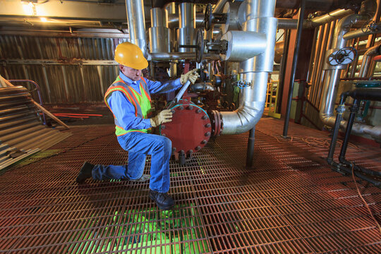 Engineer in electric power plant inspecting condenser piping