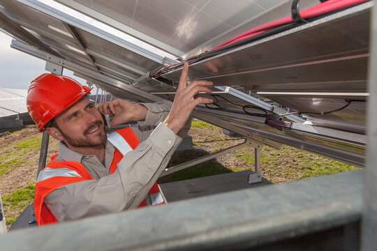 Power engineer on cell phone discussing power cabling of solar photovoltaic array