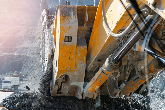 Large quarry excavator Loading gold ore into yellow dump truck for transportation to mining processing plant, view from cockpit.