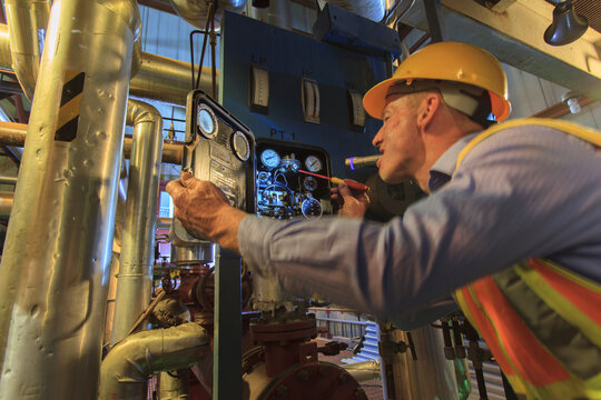 Engineer in electric power plant inspecting sensor with flash light