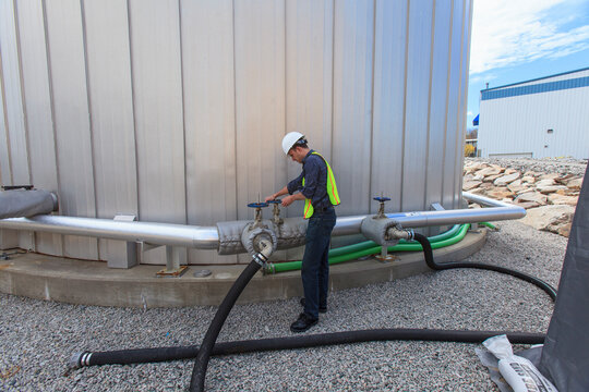 Industrial engineer turning valve on pipe at fuel tank at a power plant