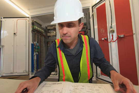 Industrial engineer reviewing electrical system plans at a power plant