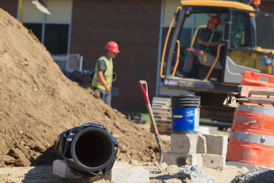 Corrosion protection sleeve over cast iron water pipe at construction site with engineers in