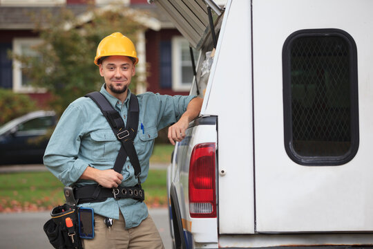 Tradesman retrieving supplies from an open hatch on the side of his work truck