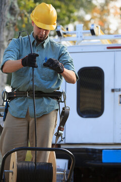 Cable lineman pulling cable from reel at site