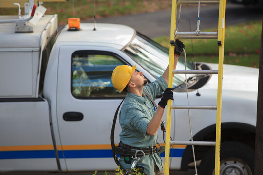 Lineman placing ladder at power pole