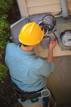Lineman working on cable at connection box at a home