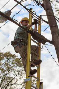 Tradesman standing on a ladder working with overhead cables