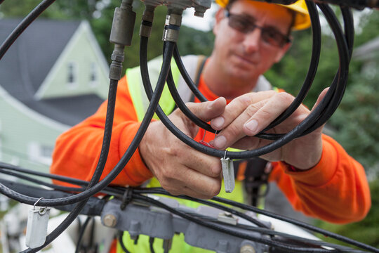 Cable lineman attaching identification tag to cable from bucket lift