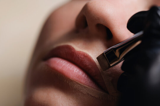 Closeup lips undergoing cosmetic tattooing in clinic, application of permanent makeup contour