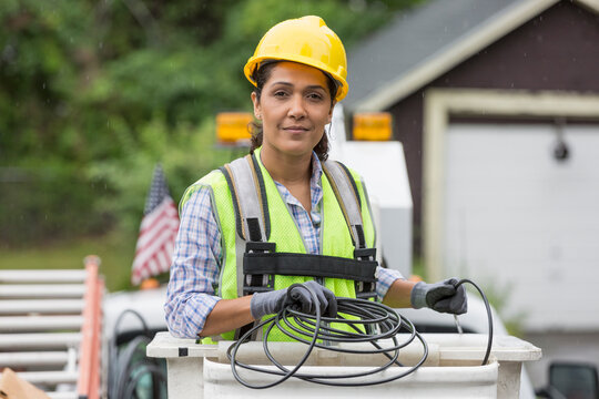 Hispanic female cable lineman in lift bucket