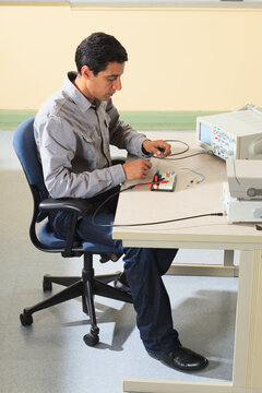 Engineering student connecting oscilloscope to measure prototyping breadboard for an electronics