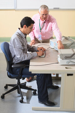 Engineering student discussing oscilloscope measurements with Professor for an electronics lab