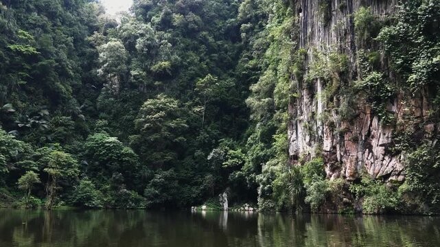 Limestone cliffs and lush tropical trees reflecting in calm water, Tasik Cermin mirror lake in Ipoh Malaysia, natural landscape background, travel and tourism destination