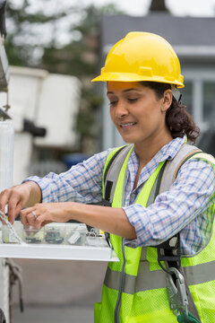 Hispanic female utility worker with box of cable amplifiers at site