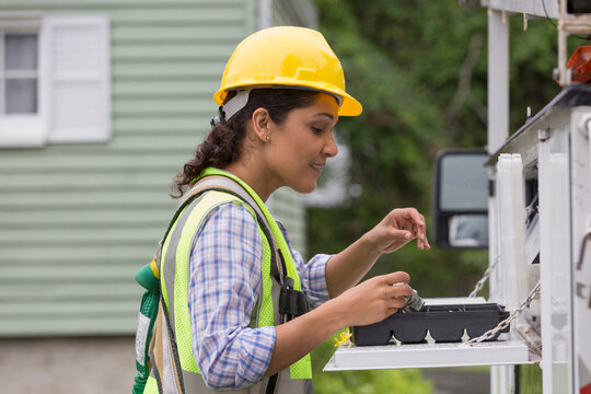 Hispanic female utility worker with tools at site